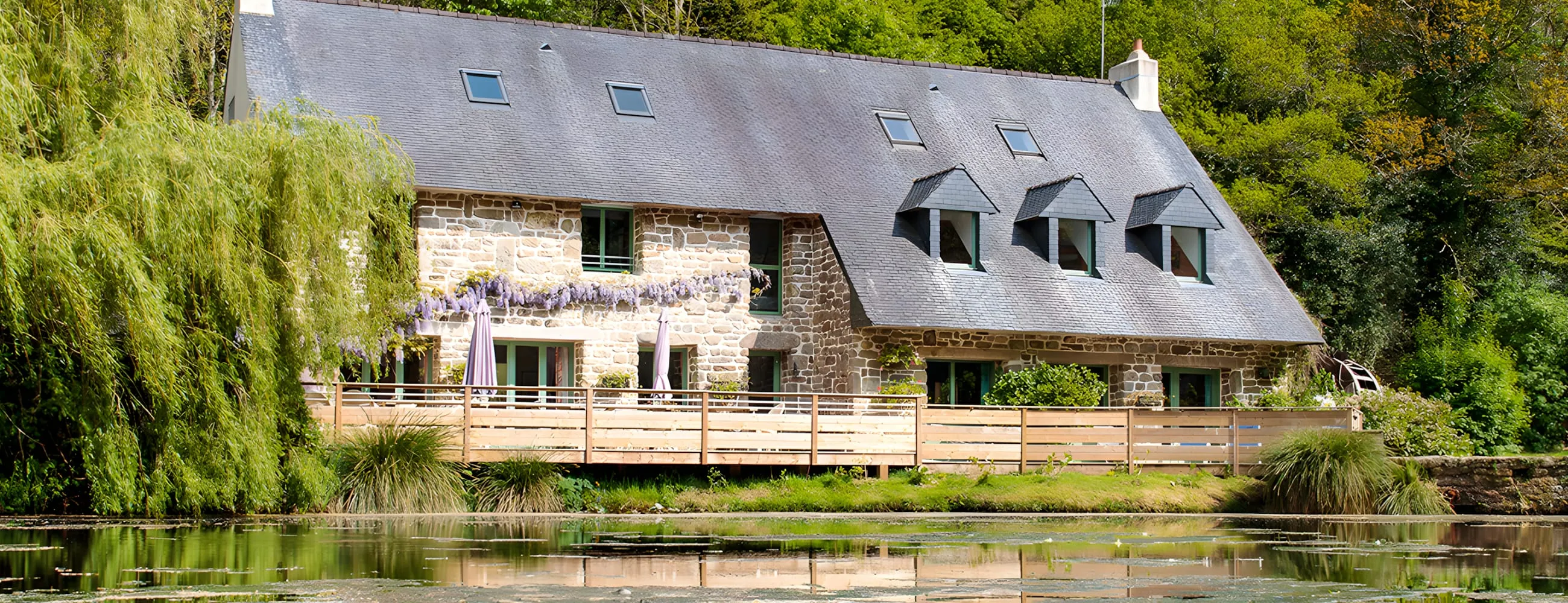 The stone Moulin La Salmonière reflected in its pond, in Brittany